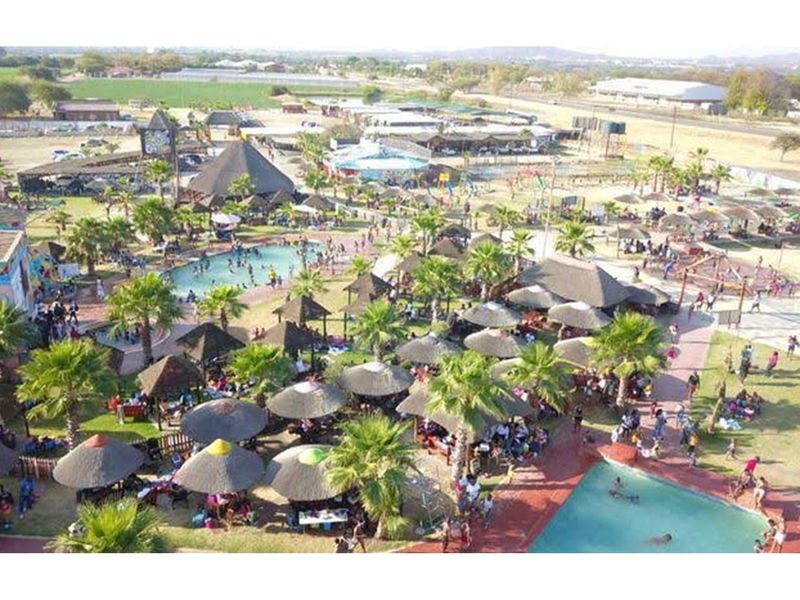 Aerial view of a large recreational retail facility featuring multiple swimming pools, thatched-roof gazebos, landscaped gardens, and extensive outdoor entertainment areas.