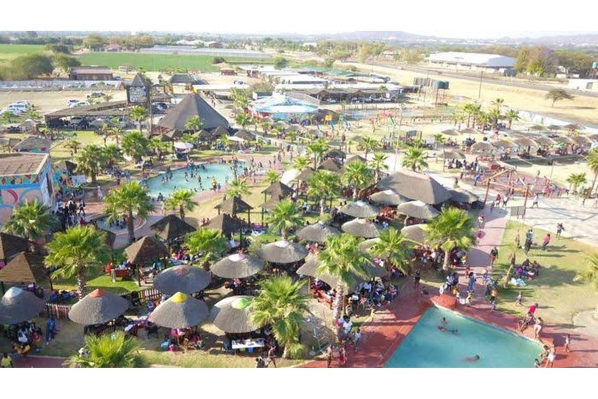Aerial view of a large recreational retail facility featuring multiple swimming pools, thatched-roof gazebos, landscaped gardens, and extensive outdoor entertainment areas.