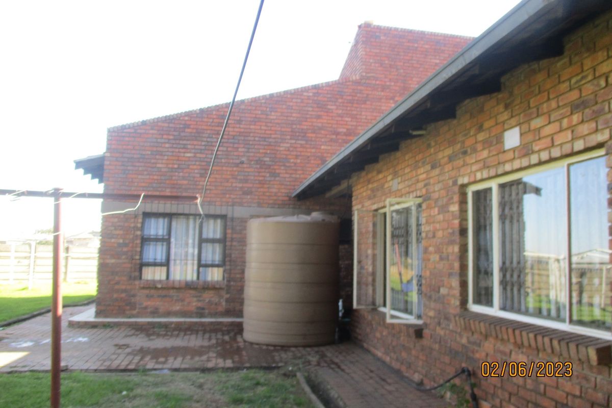 Rear exterior view of the guest house featuring face brick construction, a paved patio area, and a large water storage tank.