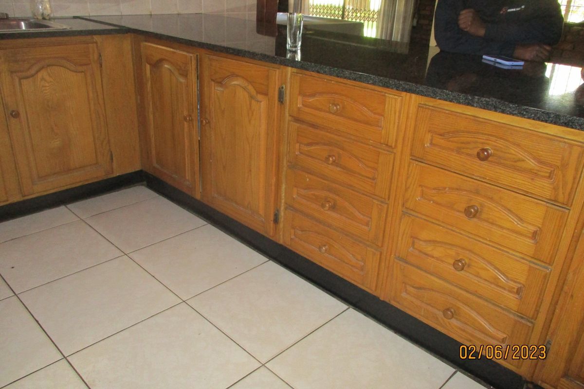 A kitchen area featuring traditional wooden cabinetry, dark granite countertops, and light-colored floor tiles.