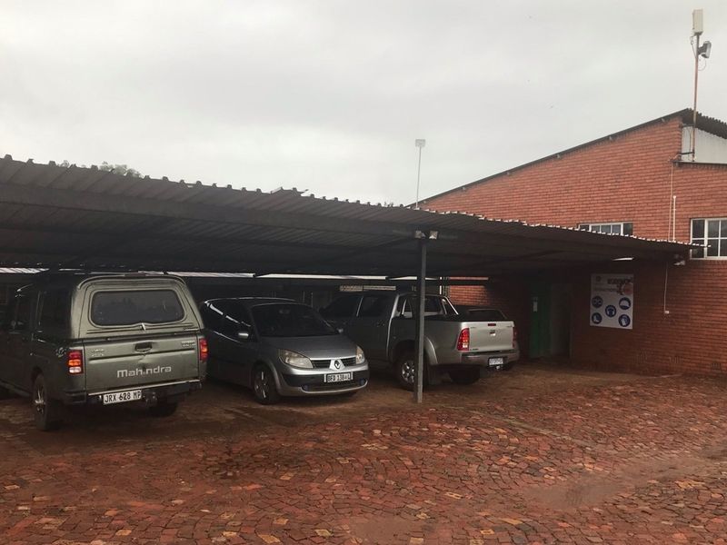Exterior view of a commercial property featuring a covered parking area with brick paving and a red brick building facade.