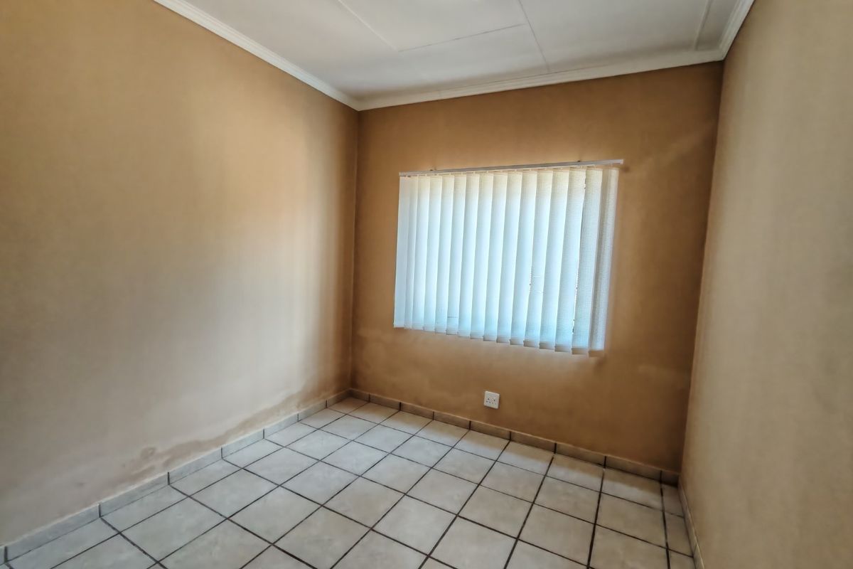 An empty bedroom featuring ceramic floor tiles, vertical blinds, and coved ceilings, presenting a blank canvas for potential renovation or interior design updates.