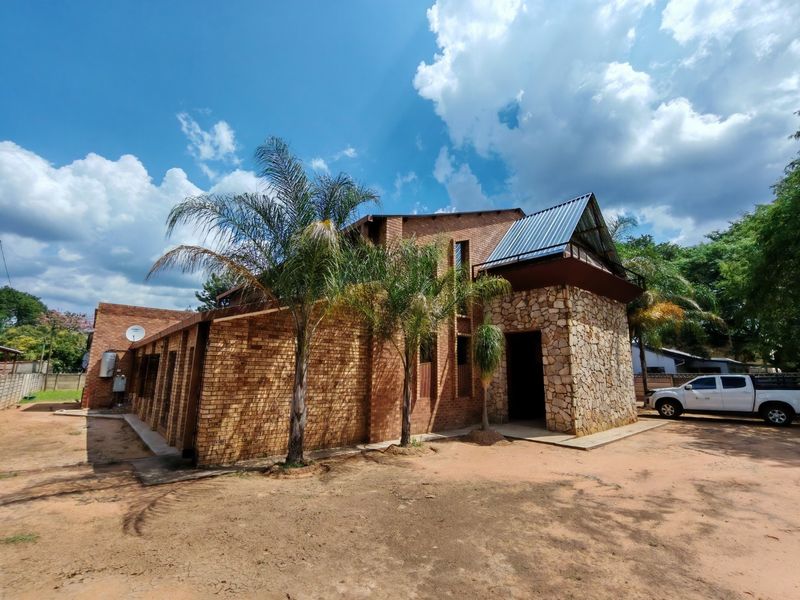 Front exterior view of a commercial building featuring a combination of face brick and stone cladding with a corrugated metal roof.
