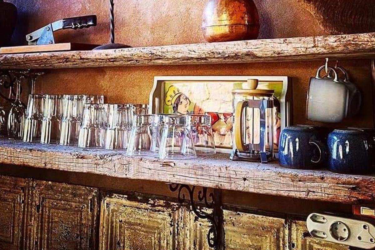 A rustic kitchen area featuring reclaimed timber shelving and decorative metal cabinet paneling, providing a unique textured aesthetic for a retail or hospitality space.