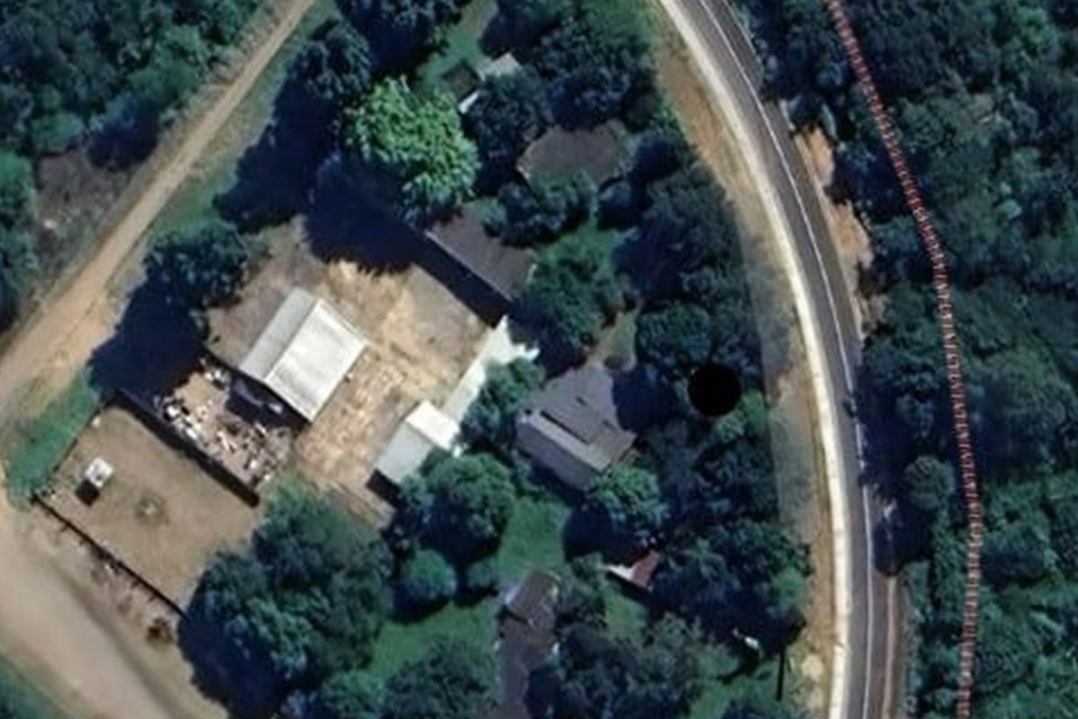 Aerial view of the commercial property site showing multiple buildings, surrounding vegetation, and access from the adjacent road.