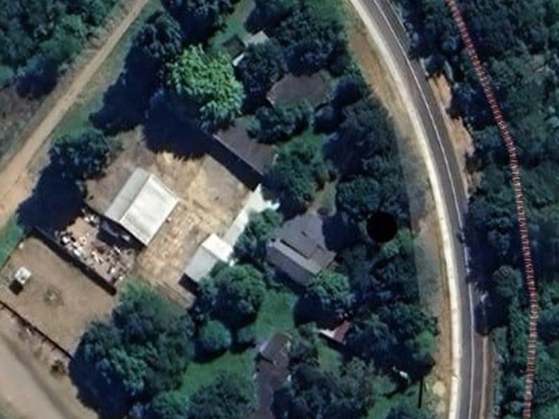 Aerial view of the commercial property site showing multiple buildings, surrounding vegetation, and access from the adjacent road.