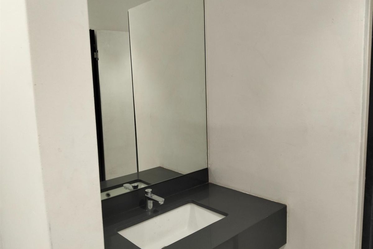 A clean, modern bathroom vanity featuring a dark stone countertop, integrated rectangular basin, and a large wall-mounted mirror.