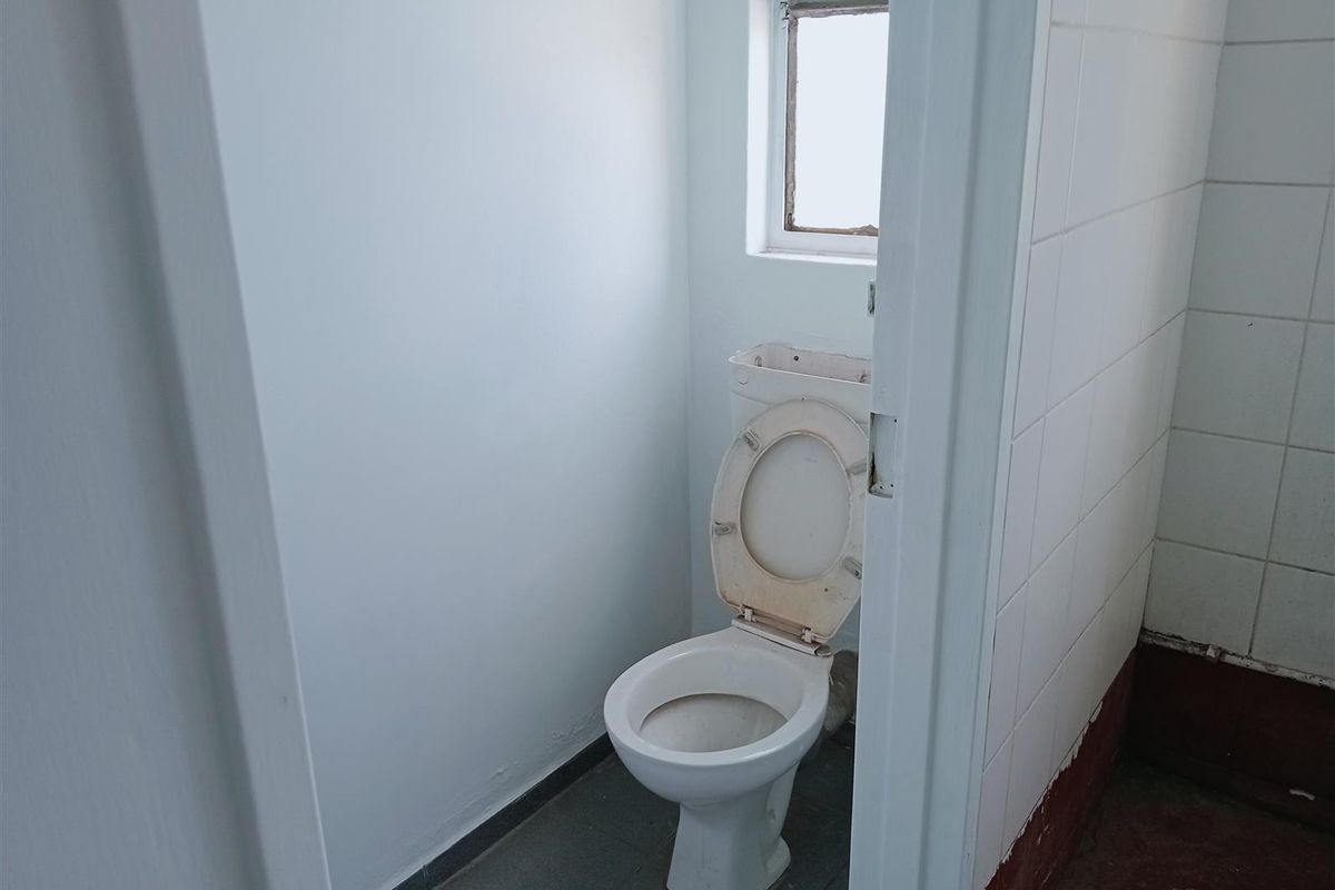 A small, functional restroom featuring a standard toilet, tiled flooring, and a window for natural ventilation.