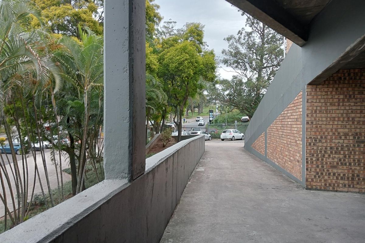 An elevated concrete walkway or ramp providing access to the industrial property, featuring exposed brickwork and views of the surrounding grounds and parking area.