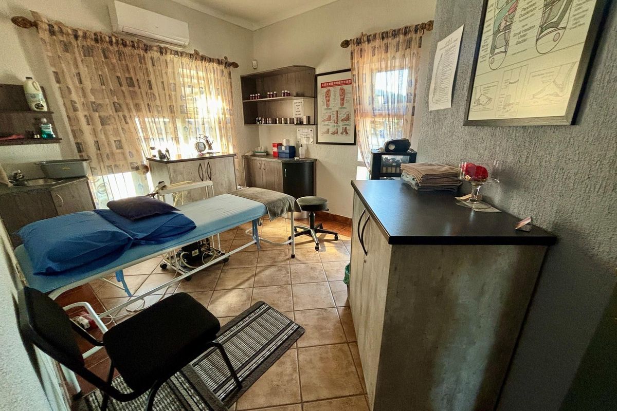 A functional treatment room featuring tiled flooring, built-in cabinetry, and a wall-mounted air conditioning unit, suitable for professional or clinical use.