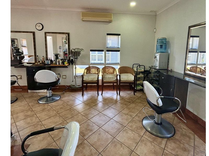 A functional retail salon space featuring tiled flooring, wall-mounted mirrors, and integrated air conditioning unit.