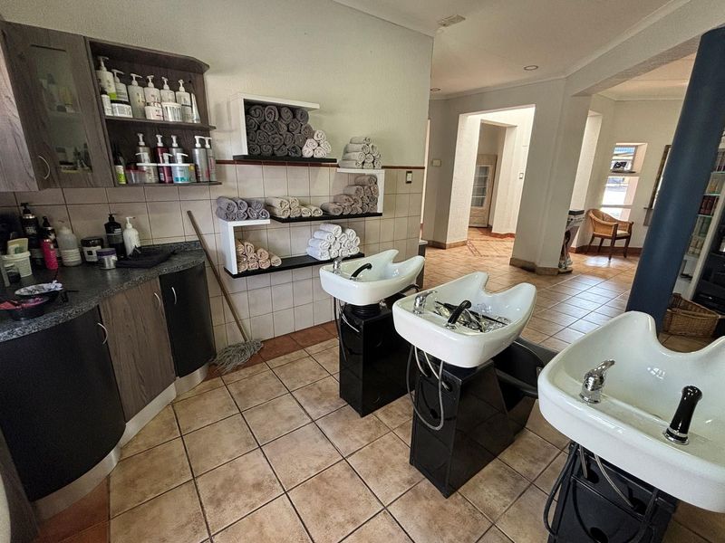 A functional salon wash area featuring three professional shampoo basins, built-in cabinetry, and open shelving for storage.