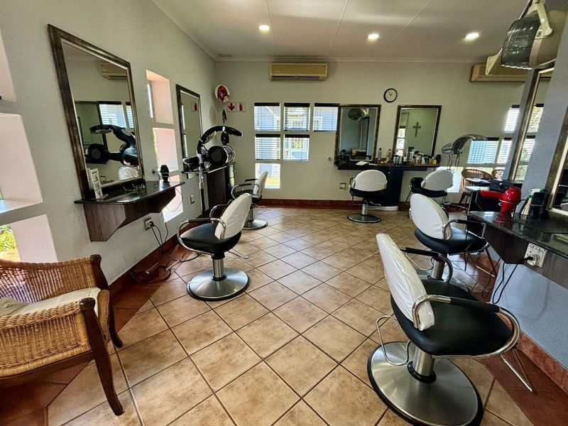 A functional salon space featuring multiple built-in vanity stations with mirrors, tiled flooring, and wall-mounted air conditioning units.