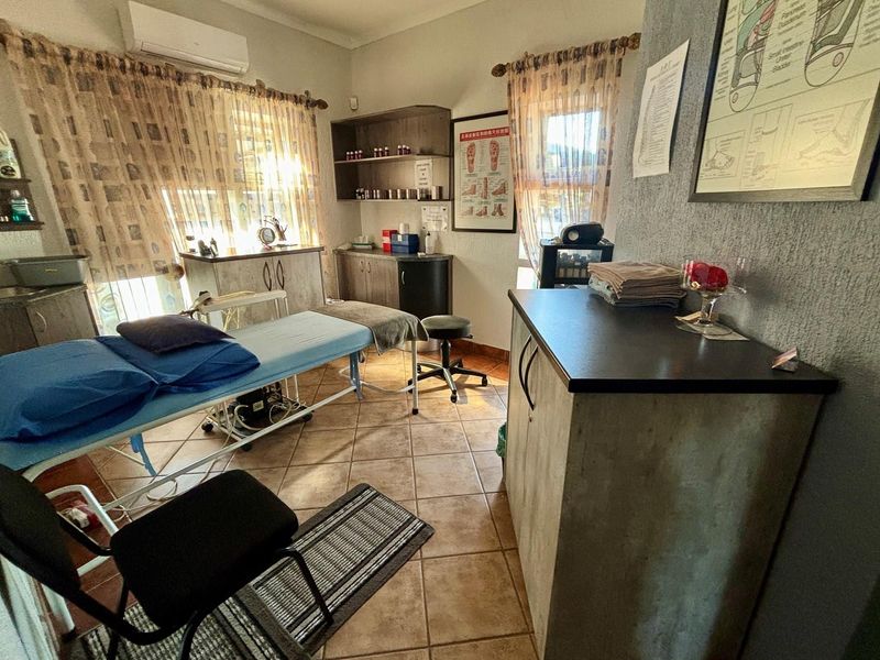 A functional treatment room featuring tiled flooring, built-in cabinetry, and a wall-mounted air conditioning unit, suitable for professional or clinical use.