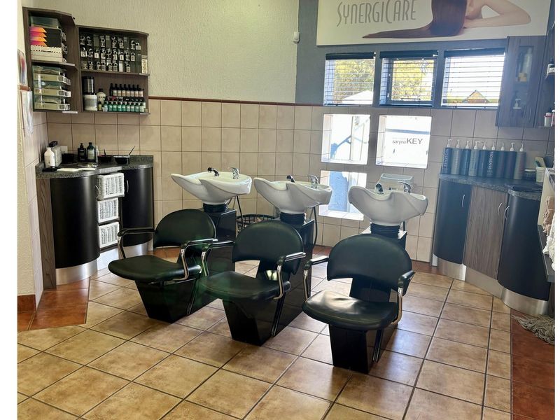 A functional salon wash area featuring three professional shampoo basins with integrated plumbing and built-in storage cabinetry.