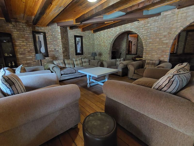 A rustic living area featuring exposed brick walls, timber ceiling beams, and arched architectural details, creating a warm and character-filled commercial space.