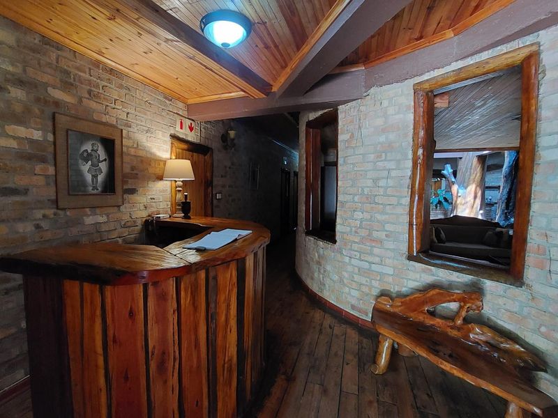 A rustic commercial entry area featuring exposed brick walls, timber ceiling, and a custom built-in wooden reception counter.