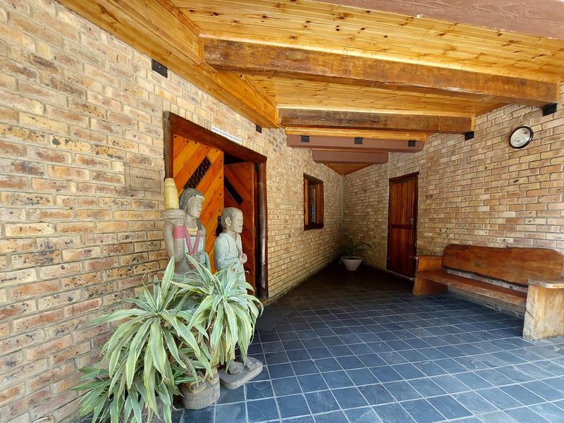 Covered entrance area featuring rustic exposed brick walls, slate tile flooring, and a timber beam ceiling, providing a welcoming and durable access point.