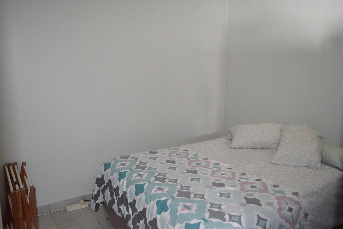 A simple bedroom space featuring tiled flooring and neutral wall finishes.