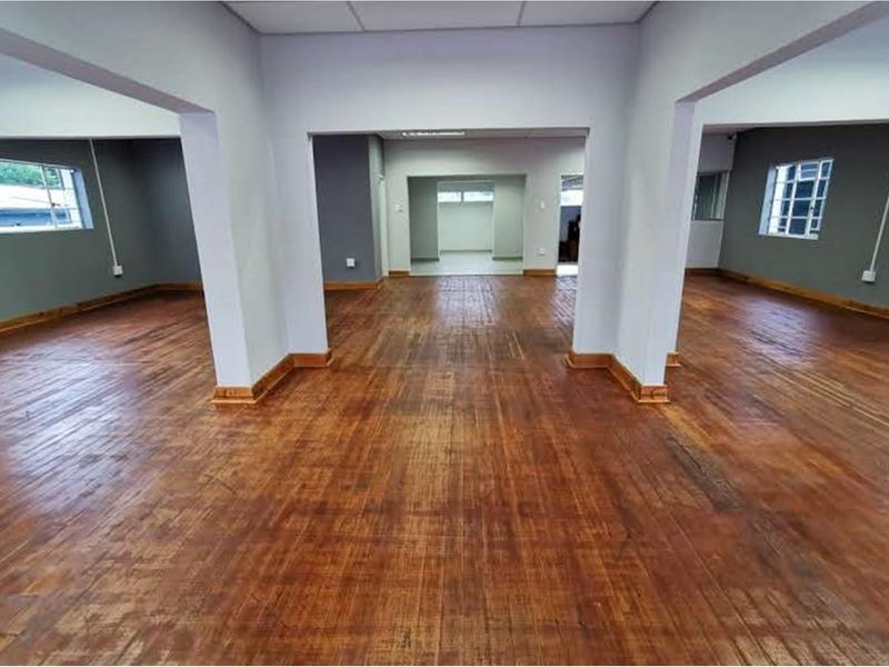 Spacious open-plan retail area featuring polished hardwood flooring, neutral wall tones, and large windows providing ample natural light throughout the interior space.