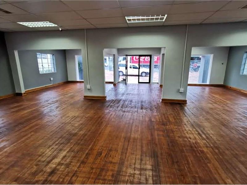 Spacious open-plan retail area featuring polished timber flooring, suspended ceilings with recessed lighting, and large windows providing natural light and street-facing visibility.