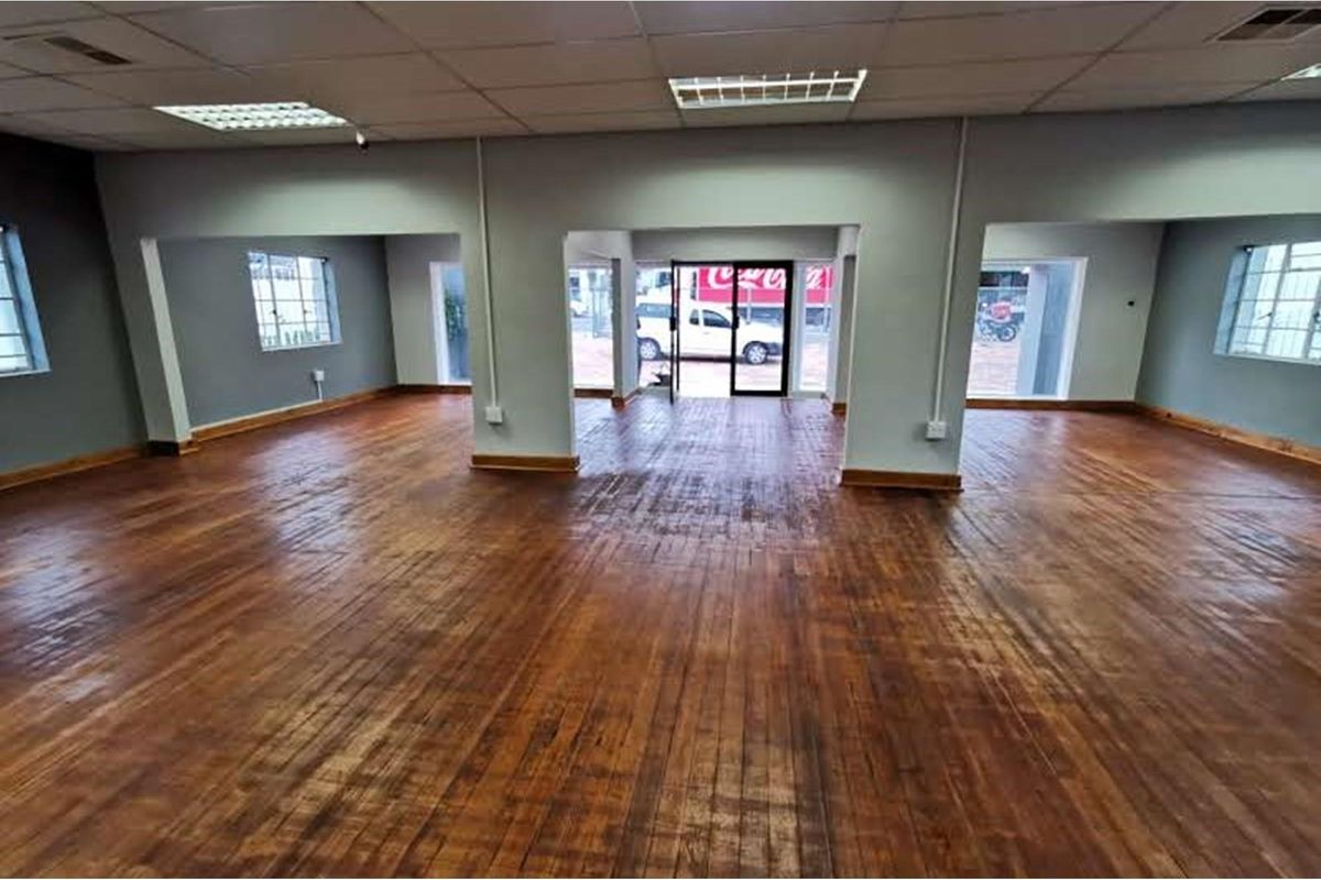 Spacious open-plan retail area featuring polished timber flooring, suspended ceilings with recessed lighting, and large windows providing natural light and street-facing visibility.