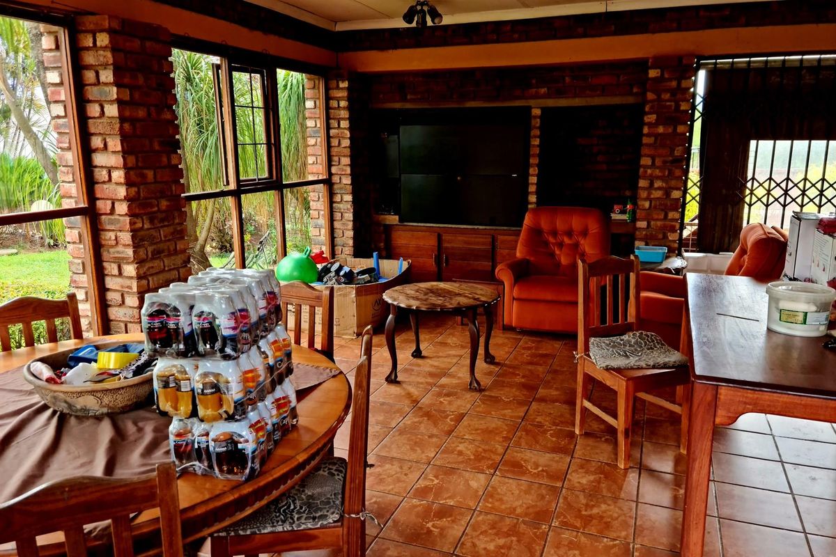 Spacious living area featuring exposed brick walls, large windows providing natural light, and tiled flooring, suitable for a comfortable family lounge or dining space.