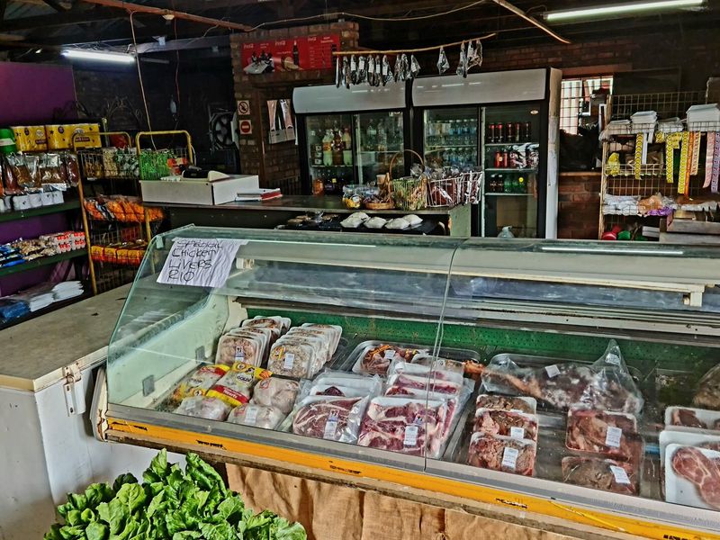 Retail space featuring a refrigerated meat display counter, shelving units, and commercial refrigeration units in a functional, industrial-style setting.