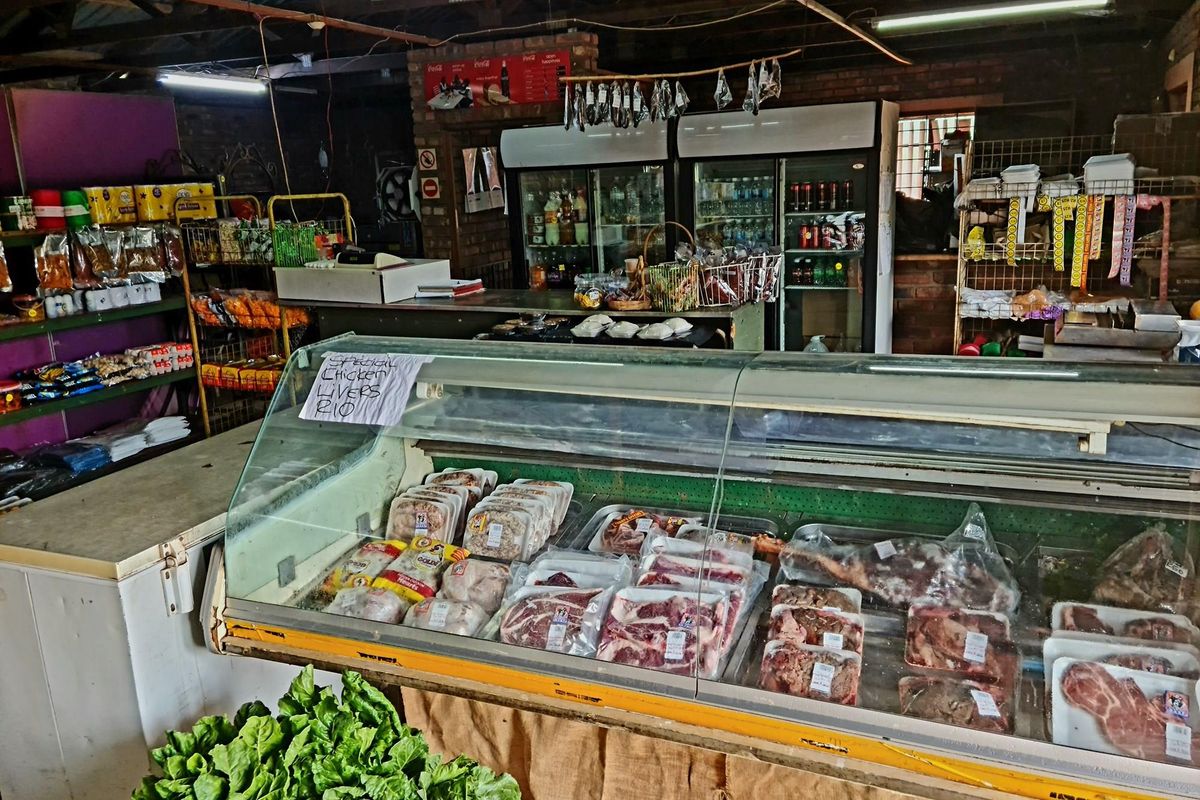 Retail space featuring a refrigerated meat display counter, shelving units, and commercial refrigeration units in a functional, industrial-style setting.