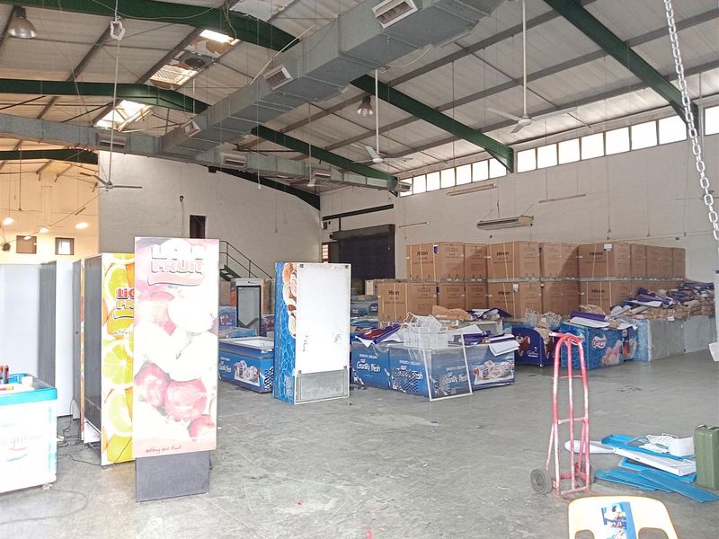 Spacious industrial warehouse featuring high ceilings with exposed steel trusses, ducted HVAC, and durable concrete flooring, suitable for storage or distribution operations.