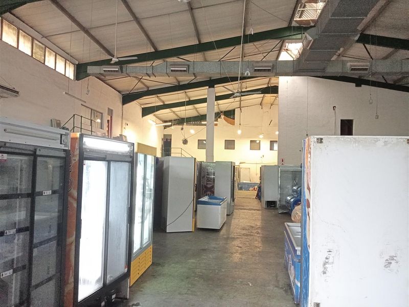 Spacious industrial utility area featuring high ceilings with exposed steel trusses, ducted HVAC, and durable concrete flooring, suitable for storage or light industrial operations.