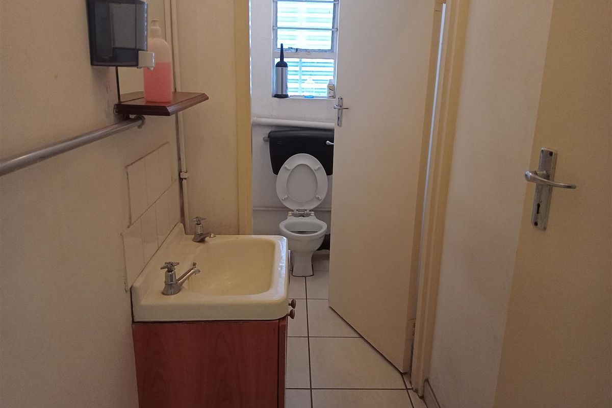 A functional bathroom featuring a vanity basin and a separate toilet area with tiled flooring and basic sanitary fixtures.