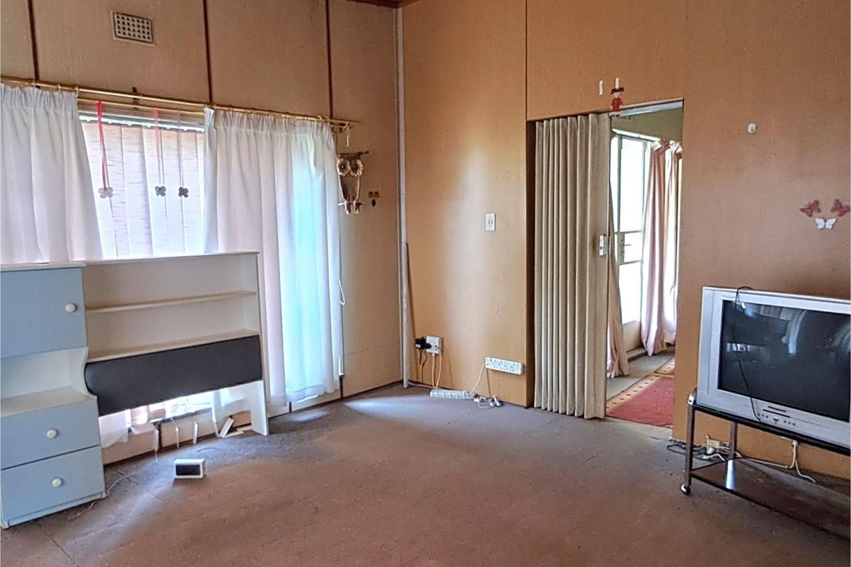 A dated living room featuring wood-paneled walls, carpeted flooring, and a folding partition door leading to an adjacent space.