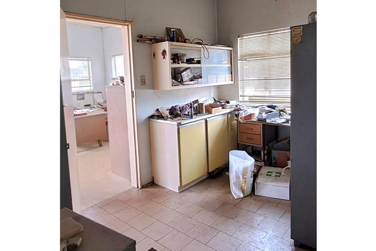 A dated utility or kitchen area featuring built-in cabinetry and tiled flooring, requiring significant renovation and modernization to restore functionality.