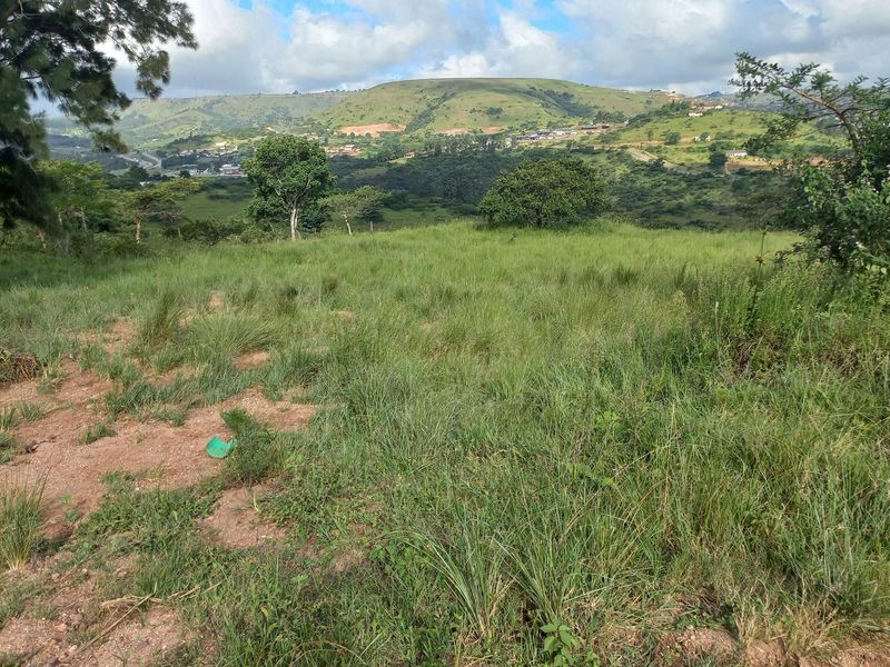 A scenic view of an undeveloped plot of land featuring natural grass and surrounding hilly landscape.