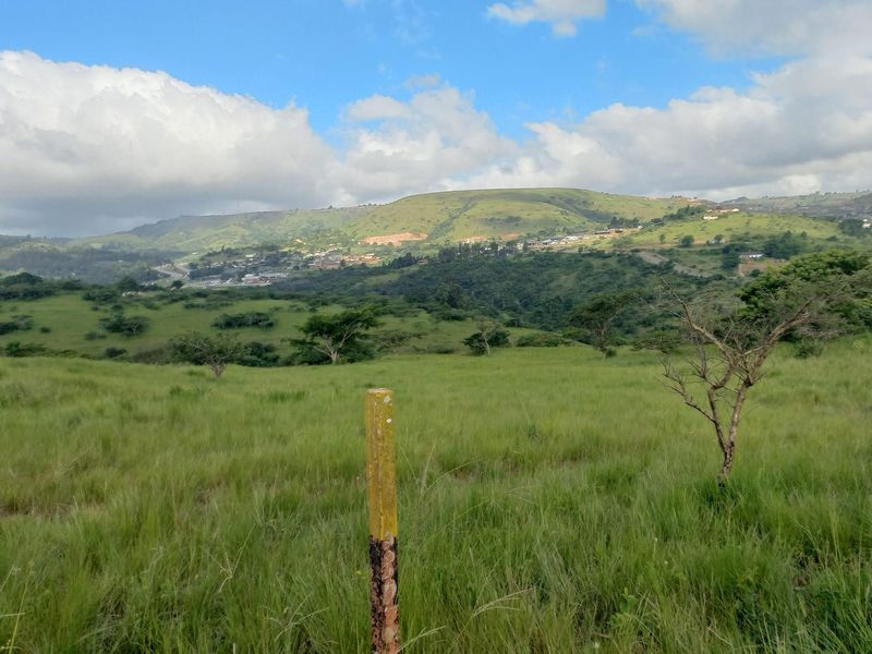 A scenic view of the surrounding landscape featuring rolling green hills and distant residential development under a partly cloudy sky.