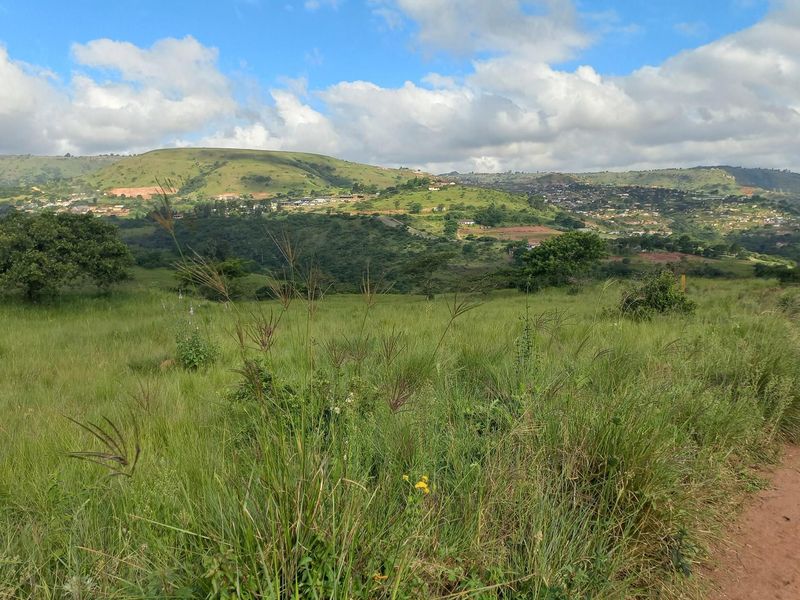 A scenic view of rolling green hills and distant residential development, showcasing the natural landscape surrounding the property.