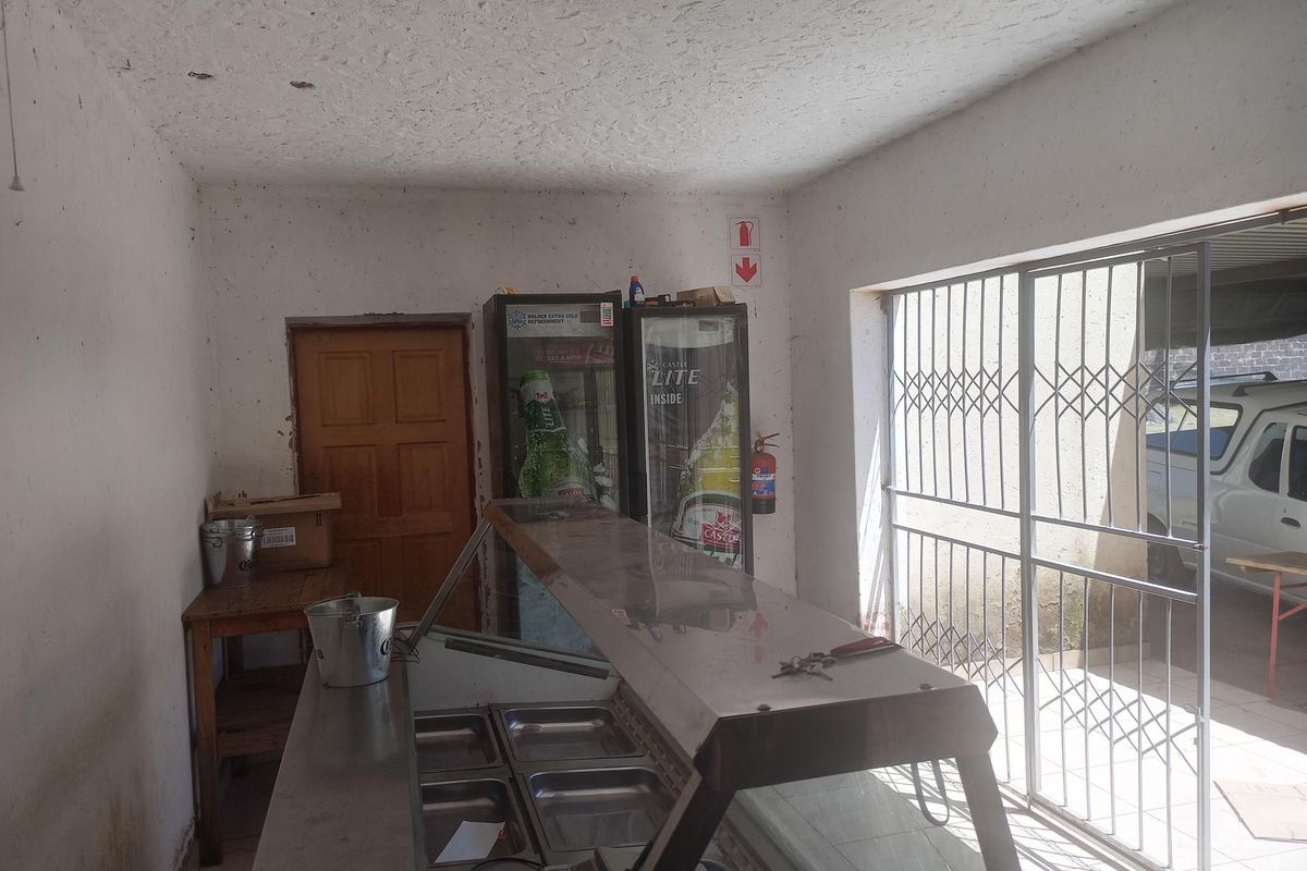 A functional retail service area featuring a stainless steel food display counter, security gate entrance, and built-in fire safety equipment.