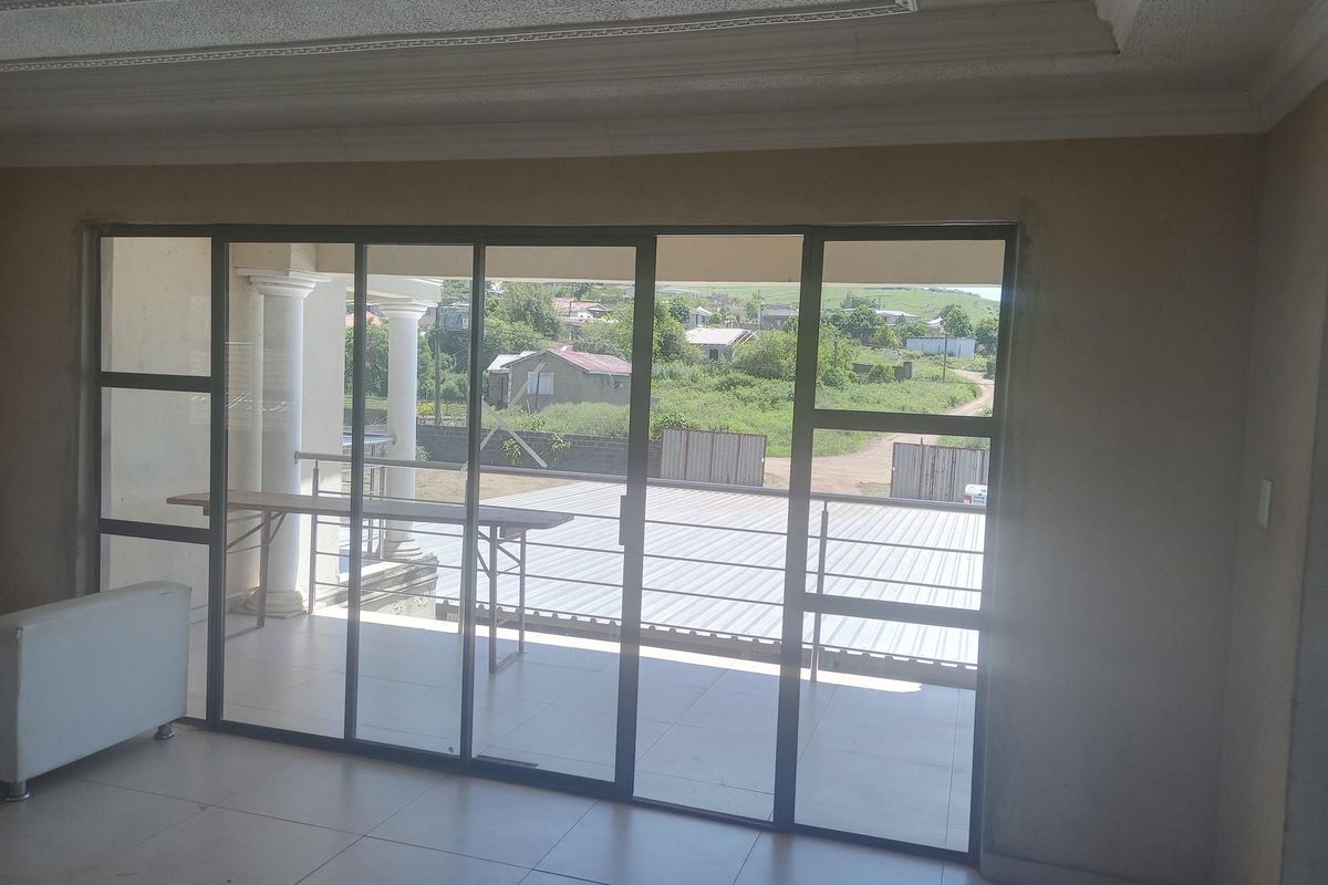Interior view of a living area featuring large sliding glass doors that open onto a covered patio with outdoor views.
