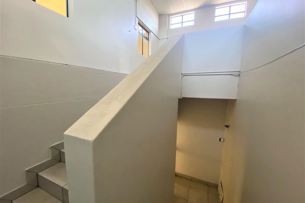 A functional interior staircase area featuring tiled steps, solid balustrades, and high-level windows providing natural light to the office circulation space.