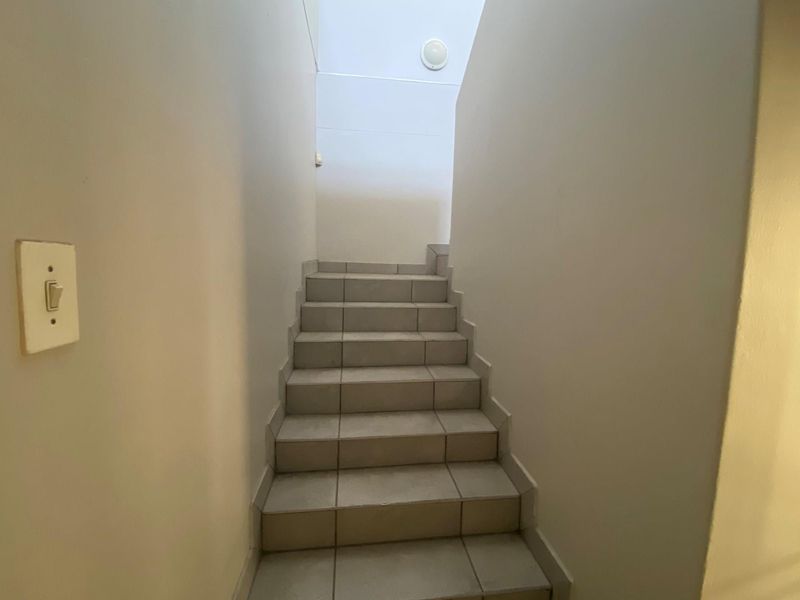 A functional staircase featuring tiled steps and plain walls, providing access between levels within the office space.