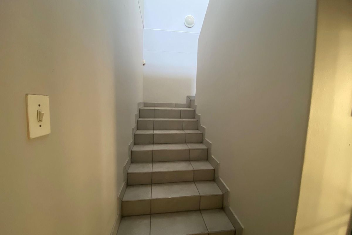 A functional staircase featuring tiled steps and plain walls, providing access between levels within the office space.