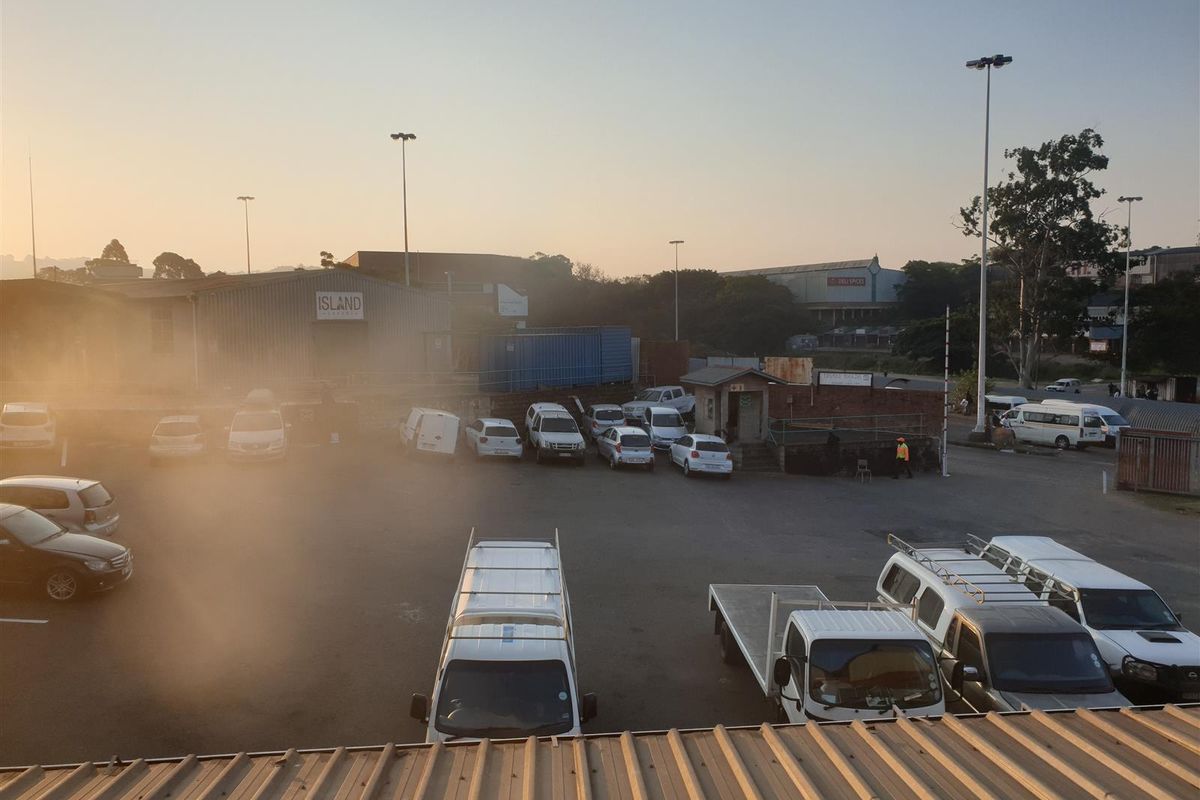An elevated view of an industrial property yard featuring paved parking areas, security lighting, and surrounding warehouse structures.