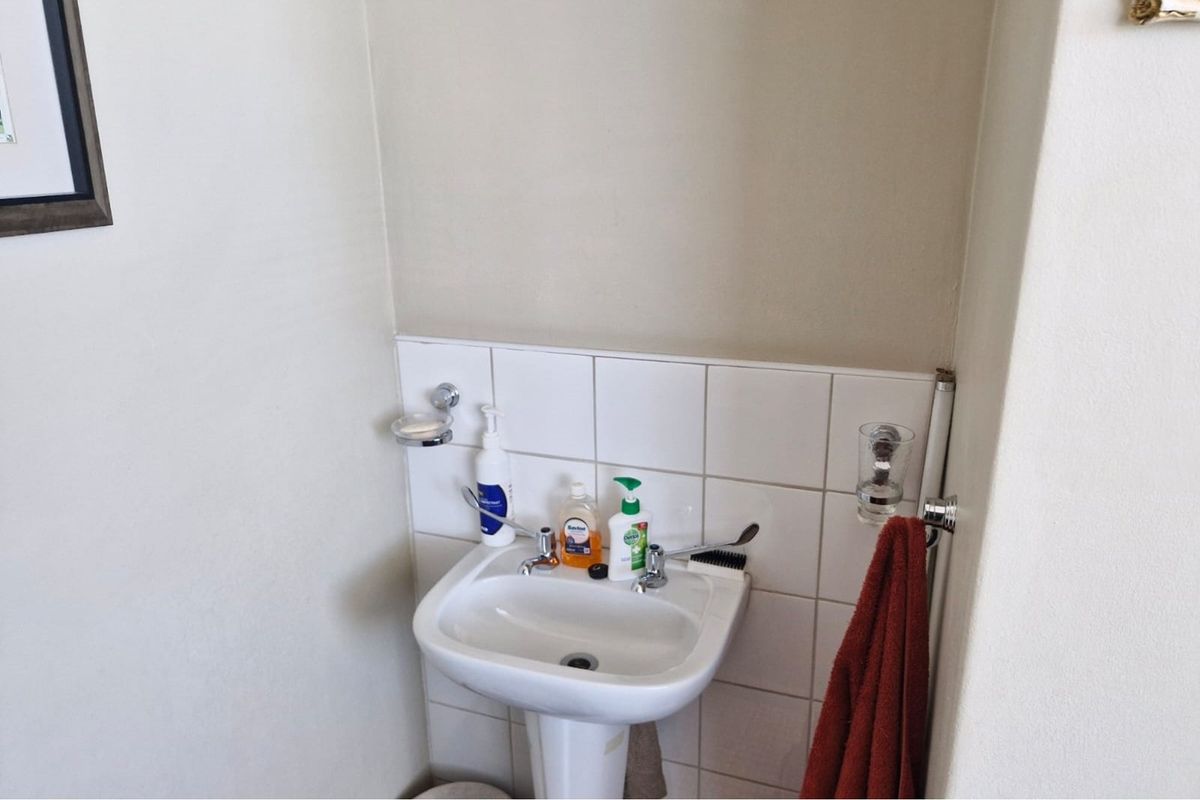 A functional bathroom area featuring a white pedestal sink with a tiled splashback and a wall-mounted towel rail.