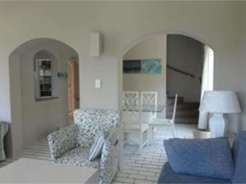 Open plan living area featuring distinctive arched doorways, tiled flooring, and a view through to the staircase and dining space.