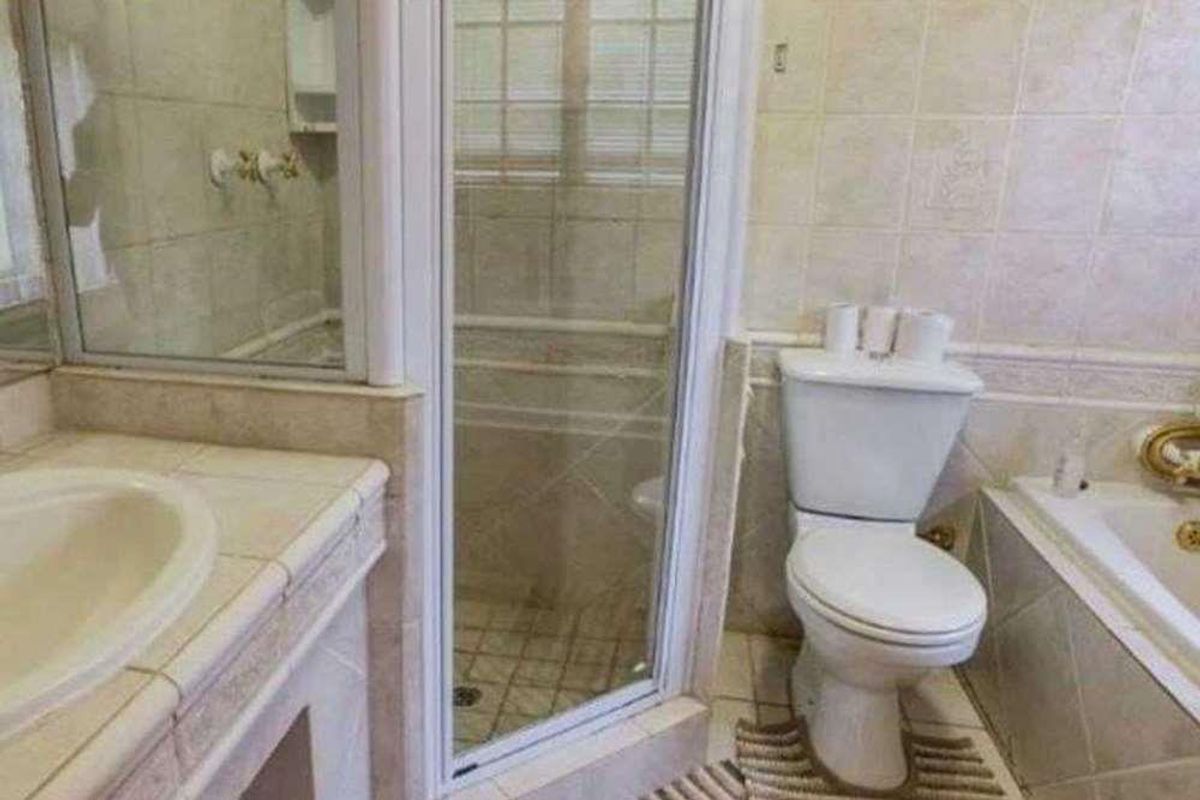 A functional bathroom featuring a tiled vanity, built-in bathtub, separate shower enclosure, and standard toilet, finished with neutral wall and floor tiles.