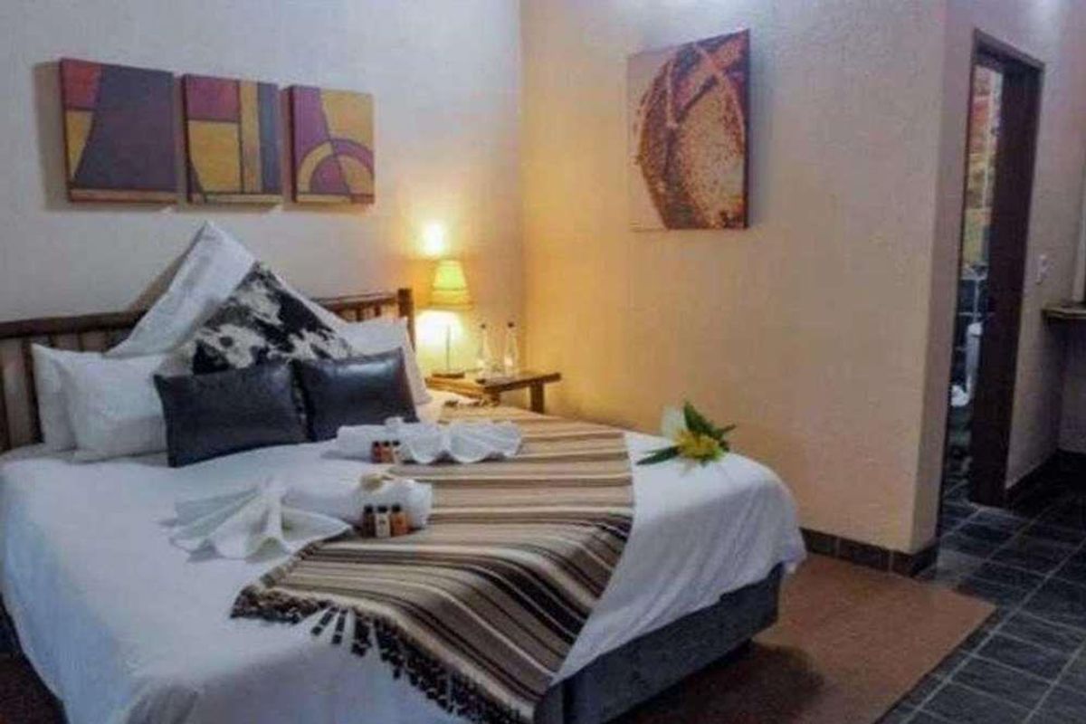 A comfortable bedroom featuring tiled flooring and direct access to an en-suite bathroom, suitable for lodge-style accommodation.