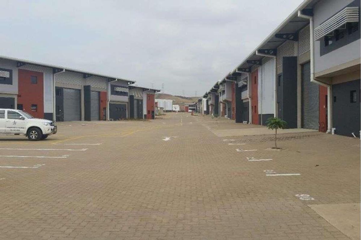 A view of a commercial industrial park featuring multiple warehouse units with roller shutter doors and paved access roads.