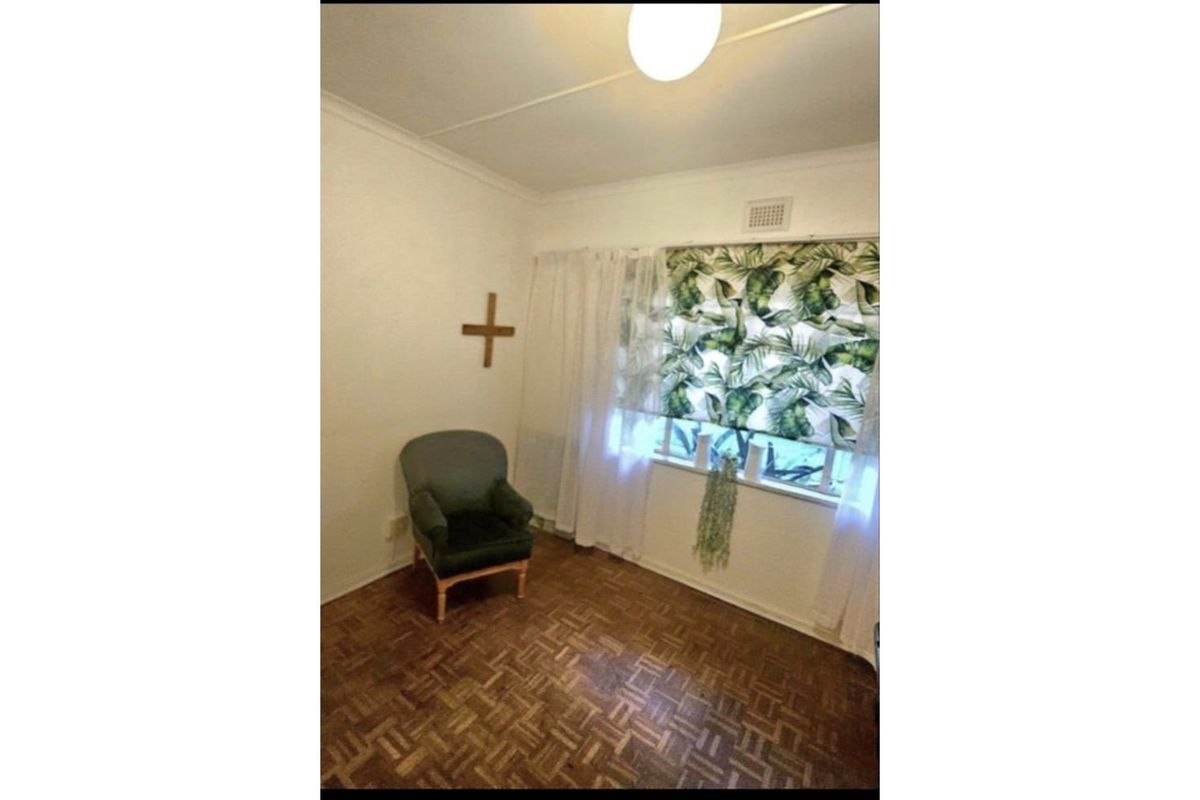 A bedroom featuring classic parquet timber flooring and a window with integrated ventilation.
