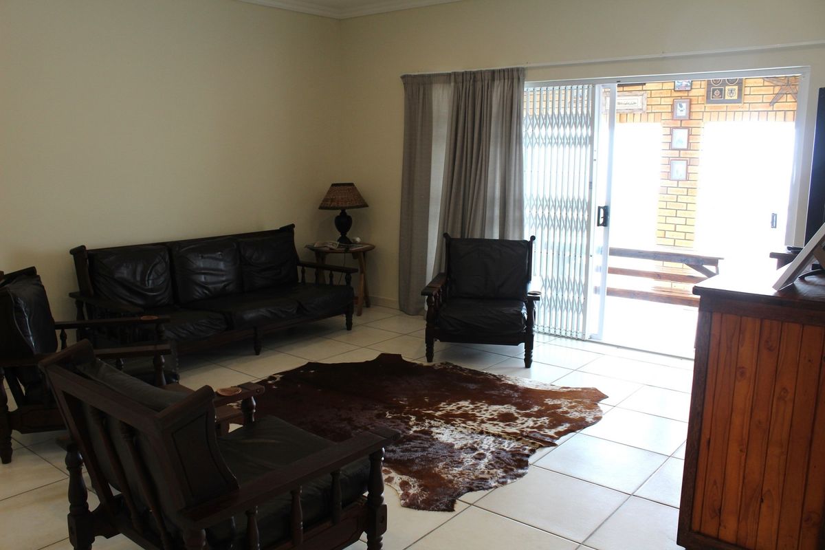 A living room featuring tiled flooring and a sliding glass door with security gate leading to an outdoor patio area.